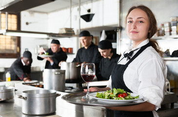 Professional waitress holding serving tray at restaurant kitchen. High quality photo
