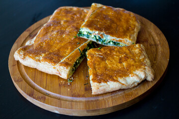 Sliced homemade layer cake with green onion and egg filling on a round wooden Board...