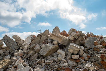A pile of concrete fragments of a destroyed building against the blue sky