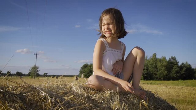 cute little girl sits on mown rye in the field 