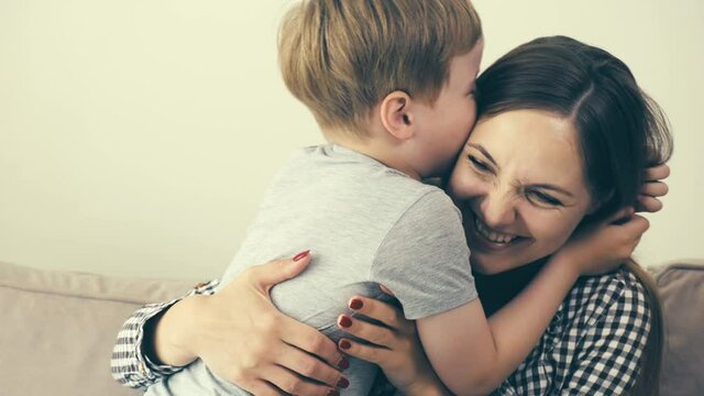 A loving young mother hugs her baby and smiles. A loving, happy family. 4k