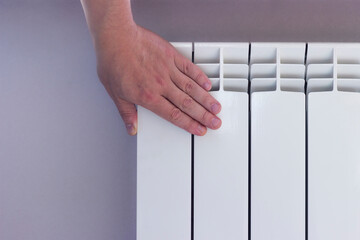 A hand touching a cold radiator while waiting for the heating season.