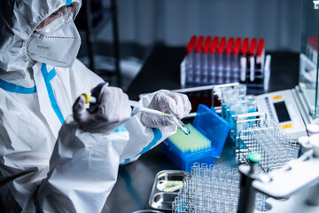 開発したワクチンを手にする防護服を着た研究員