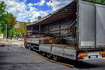 Loading metal rods and cables into cargo wagon of the truck on a city street. Semi-empty cargo box...