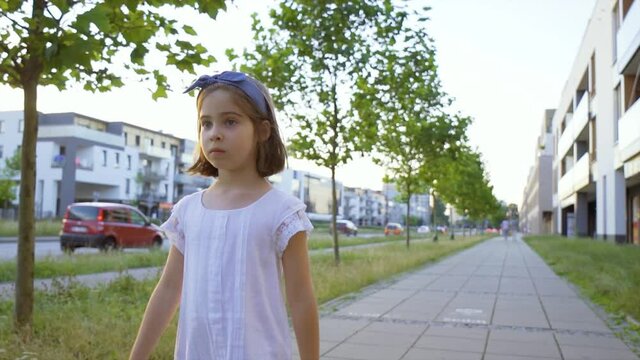 cute little girl walks along the city streets at sunset