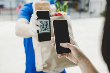 woman customer using digital mobile phone scan QR code paying for buying fresh food set bag from food delivery service man, express delivery, digital payment technology and fast food delivery concept