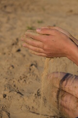 Hand clasping golden sand falling through the finger, with place for text
