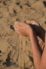 Hand clasping golden sand falling through the finger, with place for text
