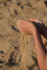 Hand clasping golden sand falling through the finger, with place for text
