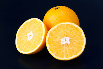Citrus fruit. Cut and whole orange on dark background