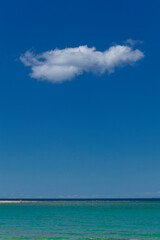 Foto minimalista con mare, sabbia e nuvola all'orizzonte.