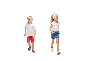 Happy kids, little and emotional caucasian boy and girl jumping and running isolated on white background. Look happy, cheerful, sincere. Copyspace for ad. Childhood, education, happiness concept.