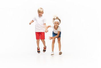 Energy. Happy kids, little emotional caucasian boy and girl jumping and running isolated on white background. Look happy, cheerful, sincere. Copyspace for ad. Childhood, education, happiness concept.