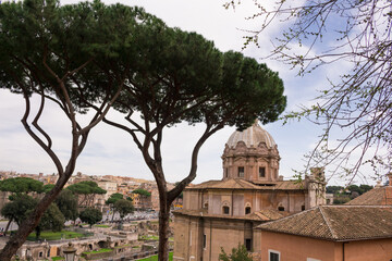 Fototapeta na wymiar View of Rome from the Capitoline hill.Behind the trees, the Church of Santa Maria Aracoeli against the background of the city and the sky