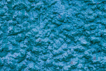 Old turquoise plaster wall texture. Retro painted putty building background with copy space. Stylish blue surface, detailed stones backdrop. Wallpaper textured screensaver front view for text design.
