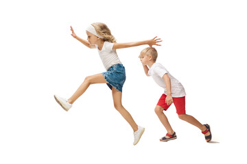 Fototapeta na wymiar Step by step. Happy kids, little emotional caucasian boy and girl jumping and running isolated on white background. Look happy, cheerful, sincere. Copyspace for ad. Childhood, education, happiness