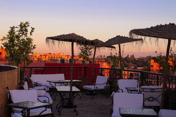 A Seating area on the roof of the Moroccan Riad with umbrellas, chairs and tables. View of the...