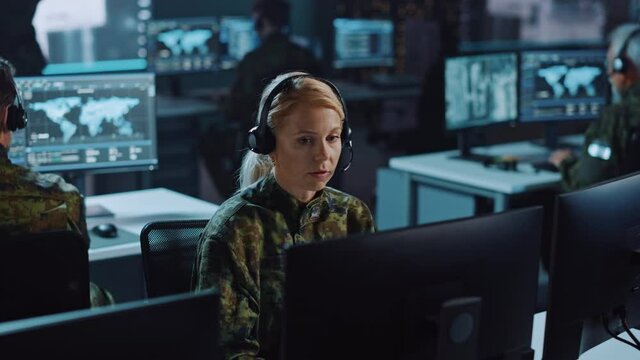 Female Military Surveillance Officer Talking on Headset in Central Office Hub for Cyber Operations, Control and Monitoring for Managing National Security, Technology and Army Communications.