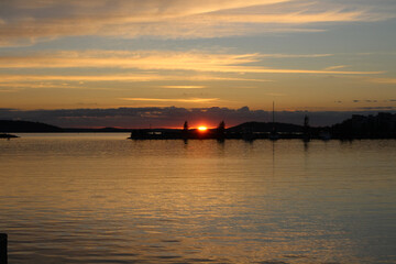 The sun sets between two trees on the shore of lake Vesijarvi. Lahti. Finland.