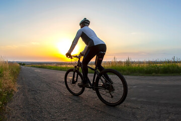 Fototapeta na wymiar cyclist rides on the road into the sunset. sports and hobbies. outdoor activities