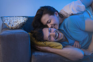 Young and happy couple watching comedy TV show