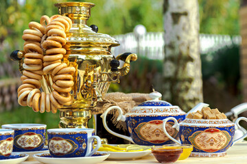 Golden samovar on the table with tea set