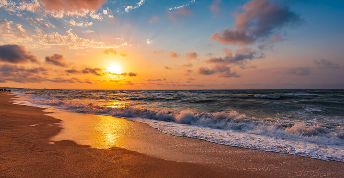 Colorful sunset with wave splashes on the beach