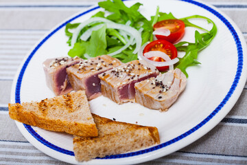 Fototapeta na wymiar Picture of tasty lightly fried tuna, served at plate with bread and greens
