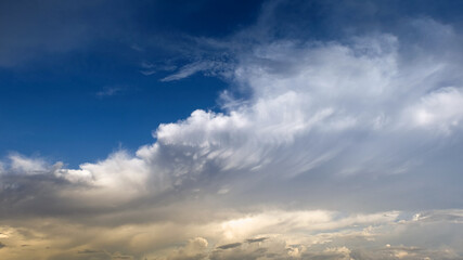Blue sky with curve white clouds and yellow sunlight.