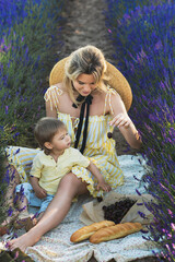 Obraz premium Young woman with her cute little son in a lavender field