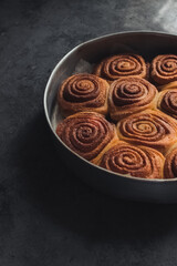 Delicious homemade raw cinnamon rolls bun dough in the rectangle shaped baking tray on the white baking paper. Top view.