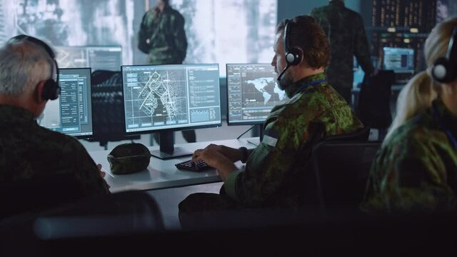 Military Surveillance Officer Working on a City Tracking Operation in a Central Office Hub for Cyber Control and Monitoring for Managing National Security, Technology and Army Communications.