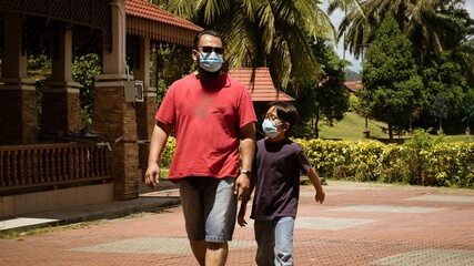 Dad and son wearing face mask walking together. Coronavirus pandemic.Family, lifestyle, fashion and quarantine. Father with child in medical mask at city street.