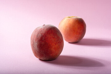 Juicy fresh peaches on a pink background.