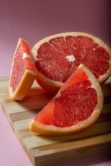 Fototapeta na wymiar Juicy sliced grapefruit on a wooden Board. Grapefruit slices on a pink background.