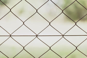 Diamond shaped wire mesh fence, green blurred background