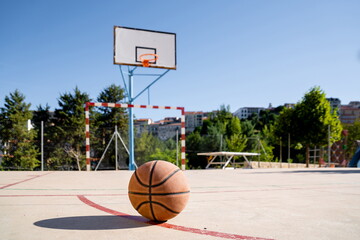 Basketball ball on a basketball court with the basket in the background