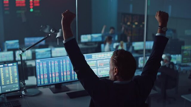Professional Financial Data Analysts Working in a Modern Monitoring Office with Live Analytics Feed on a Big Digital Screen. Monitoring Room with Finance Specialists Sit in Front of Computers. 
