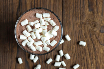 Fototapeta na wymiar Top view of hot chocolate, or smoothie or cocktail sprinkled with marshmallows. New Year's drink. Dessert or snack. Place for text. Wood background