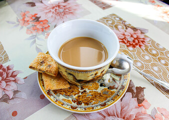 Coffee or tea with milk in a mug and next to the saucer is a cookie. Tea party.