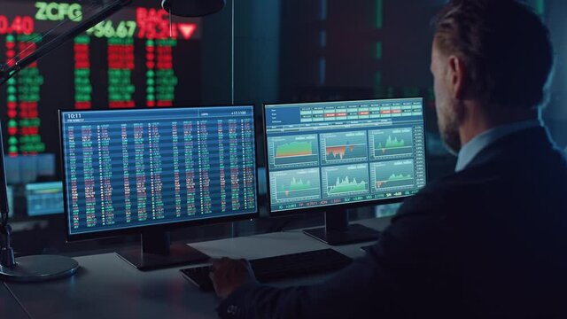 Professional Financial Data Analysts Working in a Modern Monitoring Office with Live Analytics Feed on a Big Digital Screen. Monitoring Room with Finance Specialists Sit in Front of Computers. 