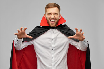 holiday, theme party and people concept - man in halloween costume of vampire and dracula cape...