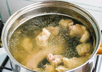 Rich meat broth in a pot in the kitchen on the stove.