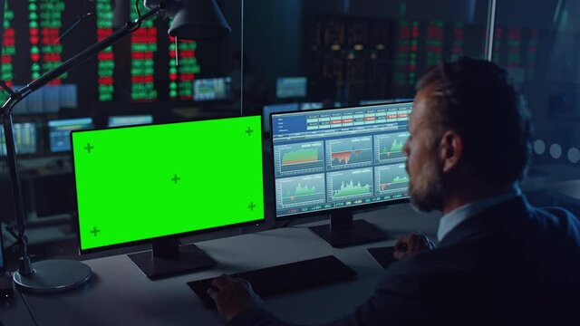 Professional Financial Data Analysts Working on a Computer with Green Screen in Modern Monitoring Office with Live Analytics Feed on a Big Digital Screen. Monitoring Room with Finance Specialists. 