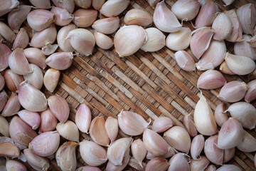 Garlic cloves on a vintage wooden bamboo weave background with space for text.