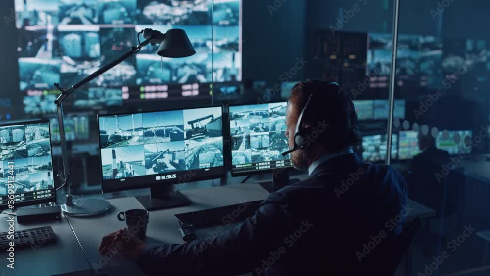 Leinwandbilder male officer works on a computer with surveillance cctv video footage in a harbour monitoring center