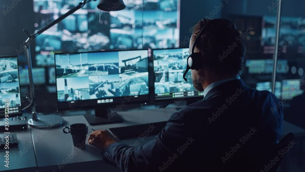 Poster male officer works on a computer with surveillance cctv video footage in a harbour monitoring center