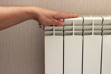 The hand checks the temperature of the radiator, whether it is cold or hot.
