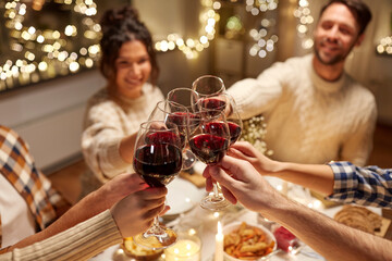 holidays, celebration and people concept - happy friends having christmas dinner at home drinking non-alcoholic red wine
