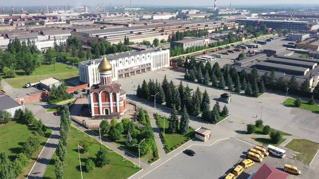 Flight over the square of the factory entrance of the machine-building plant and the church with golden domes